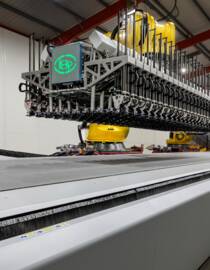 Automated cutting system with a robotic arm and a wide conveyor belt in a factory setting. Automated cutting system with a robotic arm and a wide conveyor belt in a factory setting.