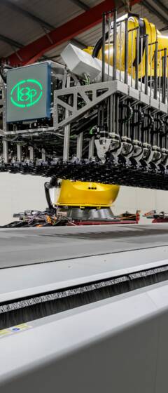 Automated cutting system with a robotic arm and a wide conveyor belt in a factory setting. Automated cutting system with a robotic arm and a wide conveyor belt in a factory setting.
