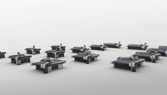 Multiple Zünd G3 L cutting systems arranged in a semi-circle on a white background, showcasing various cutter sizes. Multiple Zünd G3 L cutting systems arranged in a semi-circle on a white background, showcasing various cutter sizes.