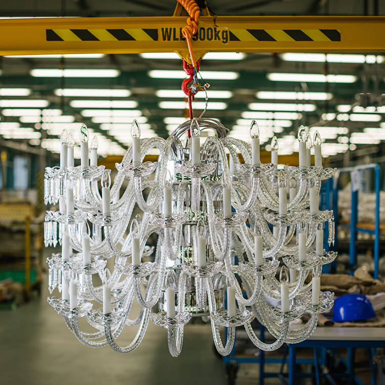 Een gedetailleerde close-up van een grote, kristallen kroonluchter met witte kaarslampen, hangend in een fabriekshal. Een gedetailleerde close-up van een grote, kristallen kroonluchter met witte kaarslampen, hangend in een fabriekshal.