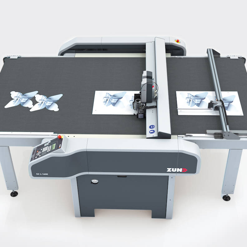 Máquina de corte Zünd S3 L-1600 cortando formas em papel, com duas borboletas já cortadas na mesa. Máquina de corte Zünd S3 L-1600 cortando formas em papel, com duas borboletas já cortadas na mesa.