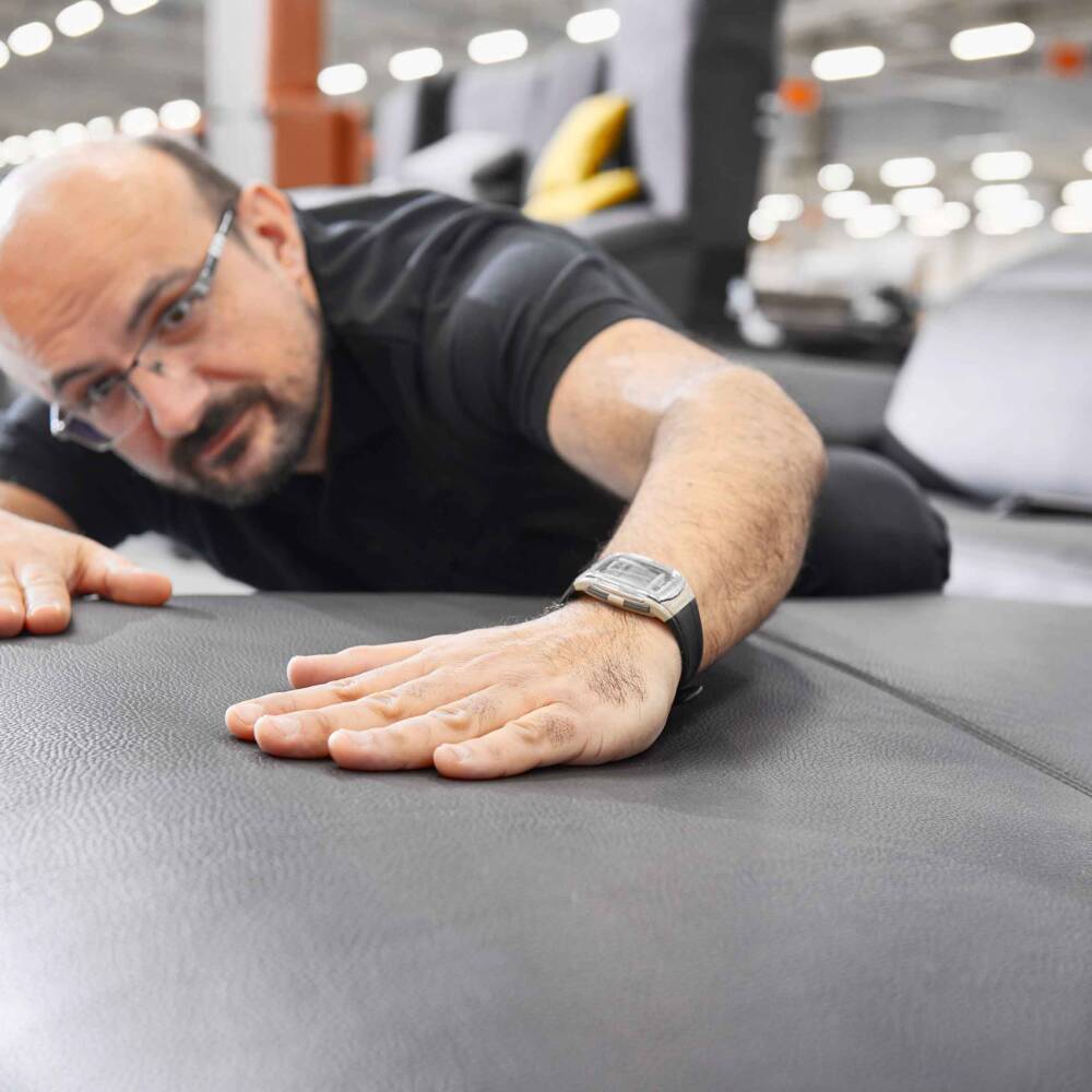 Un uomo con occhiali si sdraia su un divano di pelle grigia, esaminando attentamente la superficie. Un uomo con occhiali si sdraia su un divano di pelle grigia, esaminando attentamente la superficie.