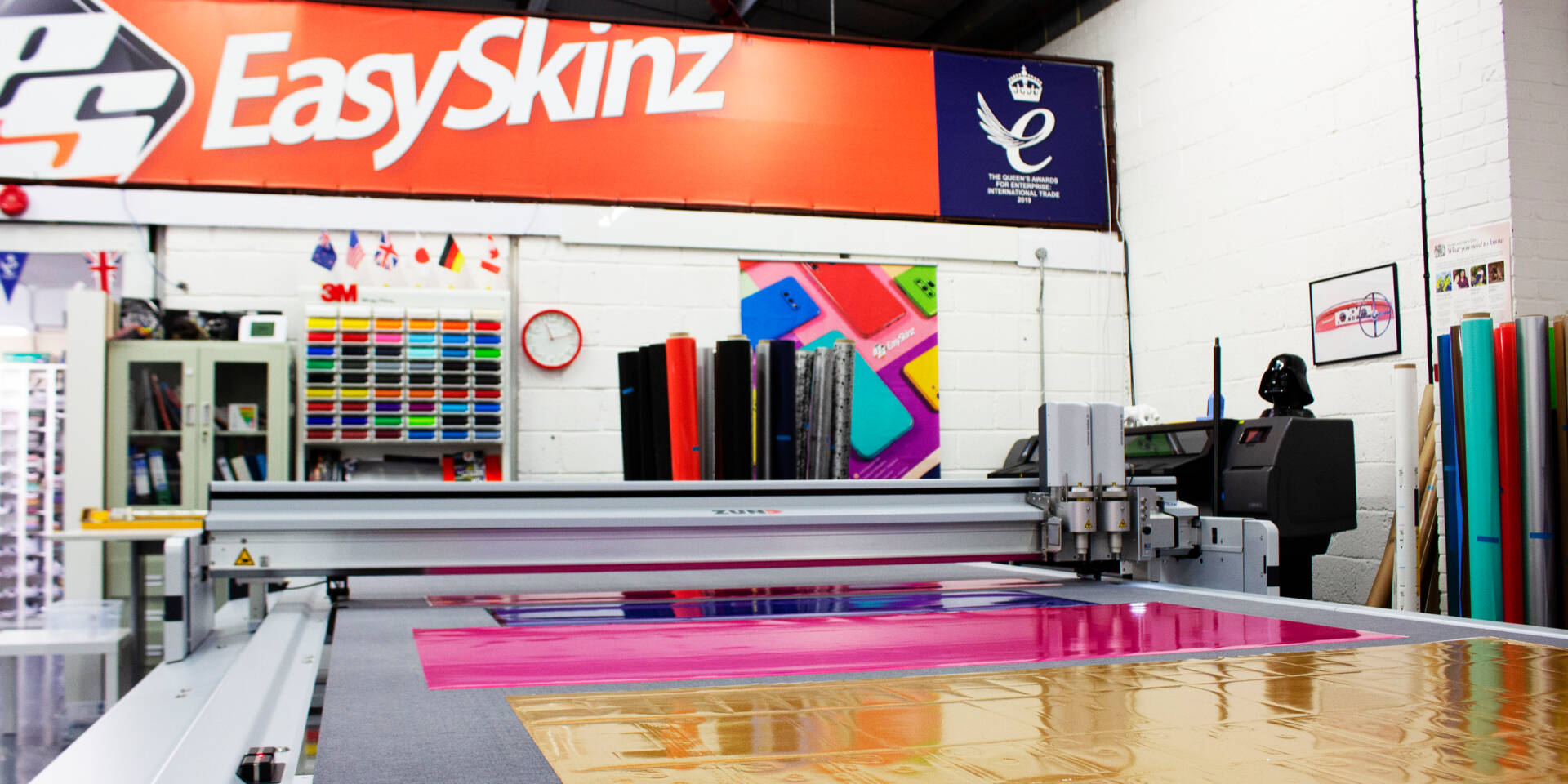 A Zünd G3 L-3200 digital cutting machine precisely cuts colorful vinyl sheets in a workshop environment. Features EasySkinz branding.