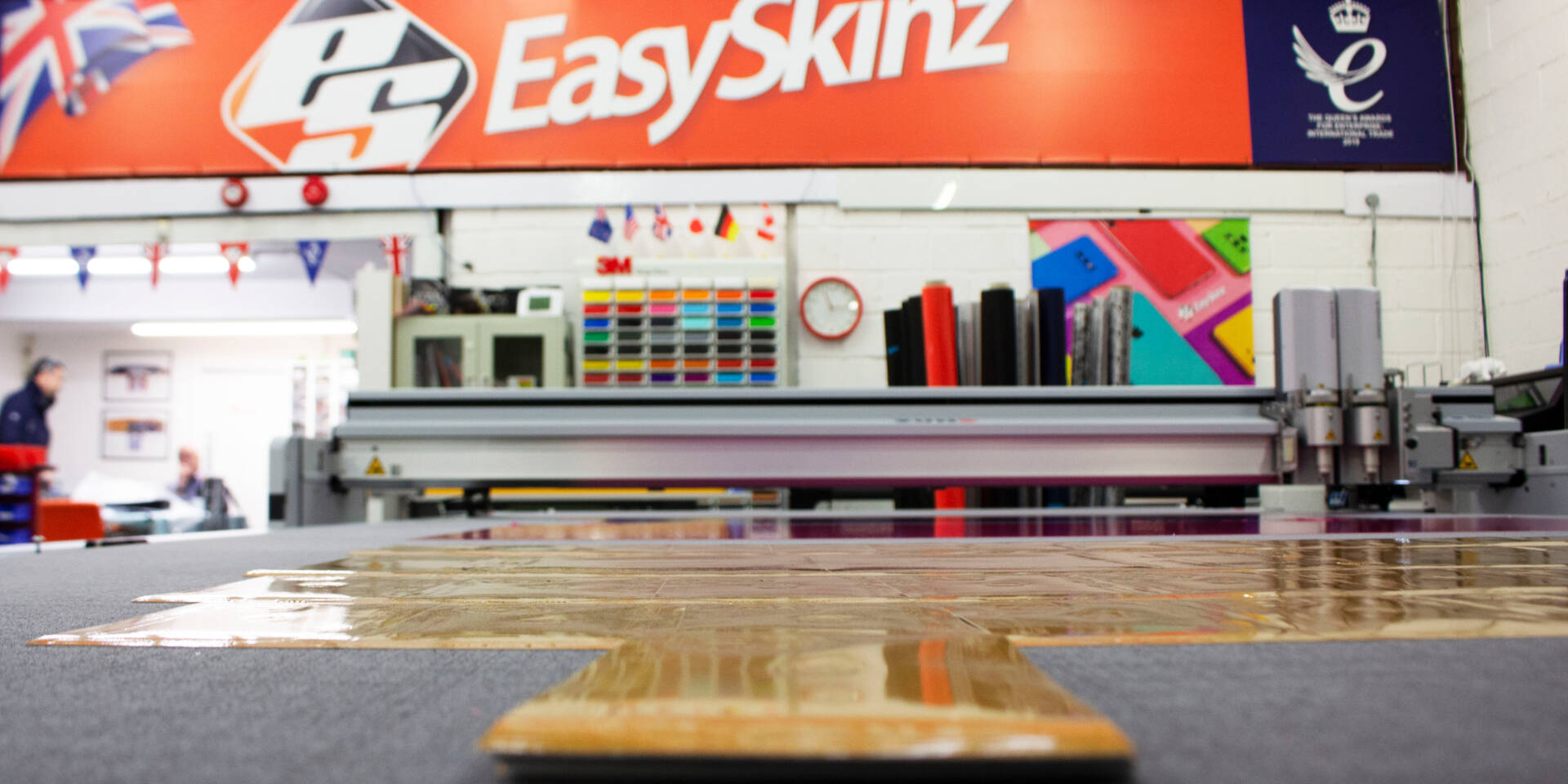 Zünd cutting machine with EasySkinz branding, rolls of material, and colorful samples in the background.