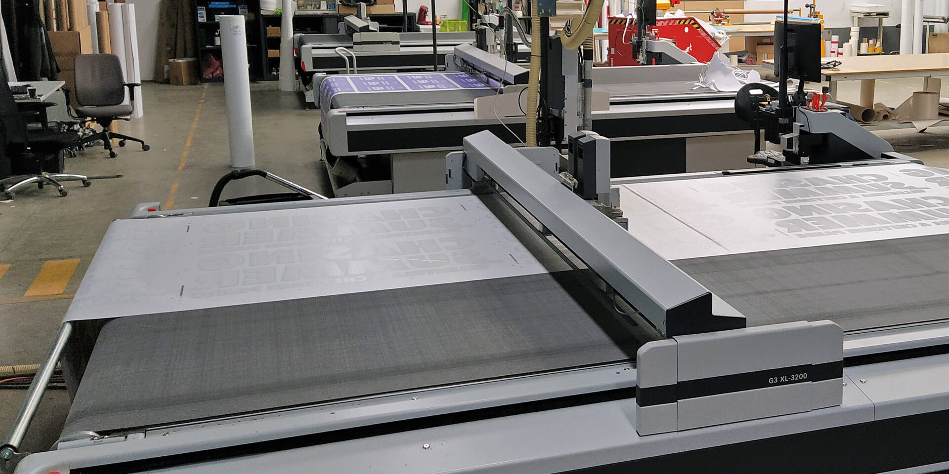 Zünd G3 XL-3200 snijtafel met grote letters op het materiaal in een werkplaatsomgeving.