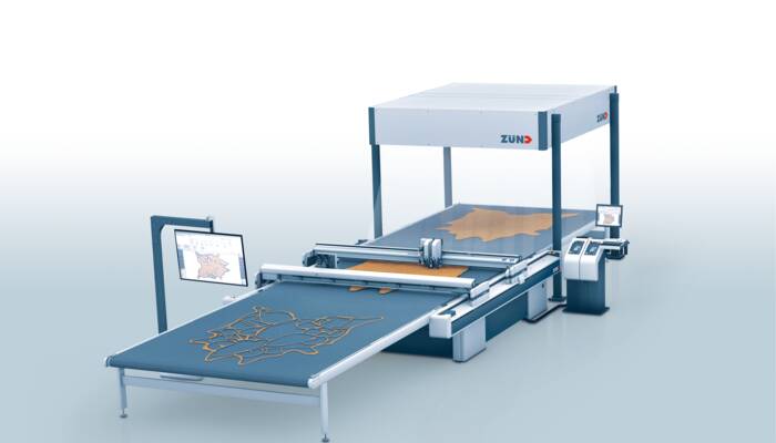 Zünd D3 2XL-3200 Cutter mit Projektionssystem schneidet Lederteile auf einem Förderband. Zünd D3 2XL-3200 Cutter mit Projektionssystem schneidet Lederteile auf einem Förderband.