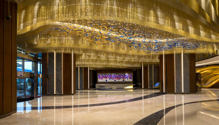 Moderne lobby met een grote gouden plafonddecoratie met blauwe accenten en marmeren pilaren. Moderne lobby met een grote gouden plafonddecoratie met blauwe accenten en marmeren pilaren.