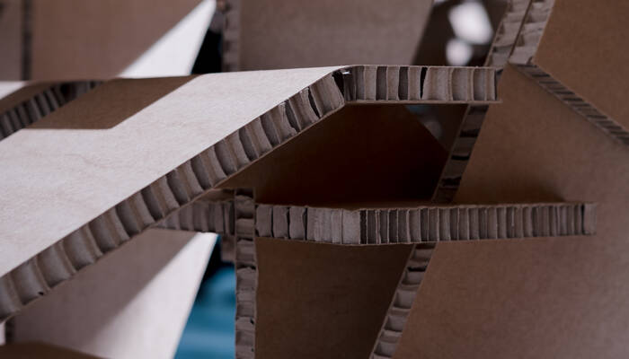 Struttura geometrica in cartone ondulato marrone e bianco, tagliata con precisione, con bordi visibili. Struttura geometrica in cartone ondulato marrone e bianco, tagliata con precisione, con bordi visibili.