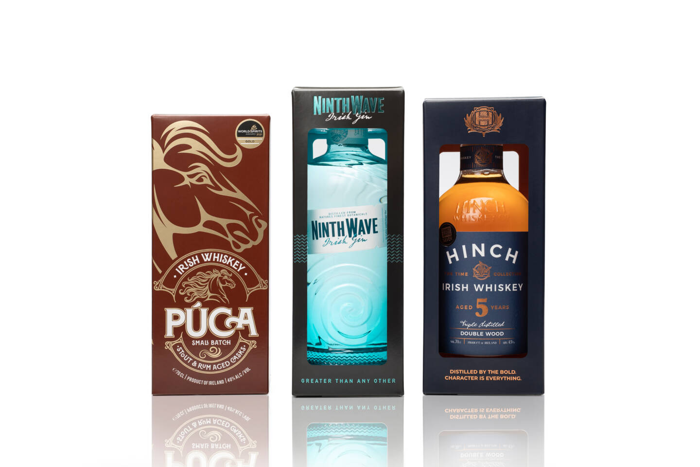 Three bottles of Irish whiskey and gin, Púca, Ninth Wave, and Hinch, displayed in their gift boxes on a white background. Three bottles of Irish whiskey and gin, Púca, Ninth Wave, and Hinch, displayed in their gift boxes on a white background.